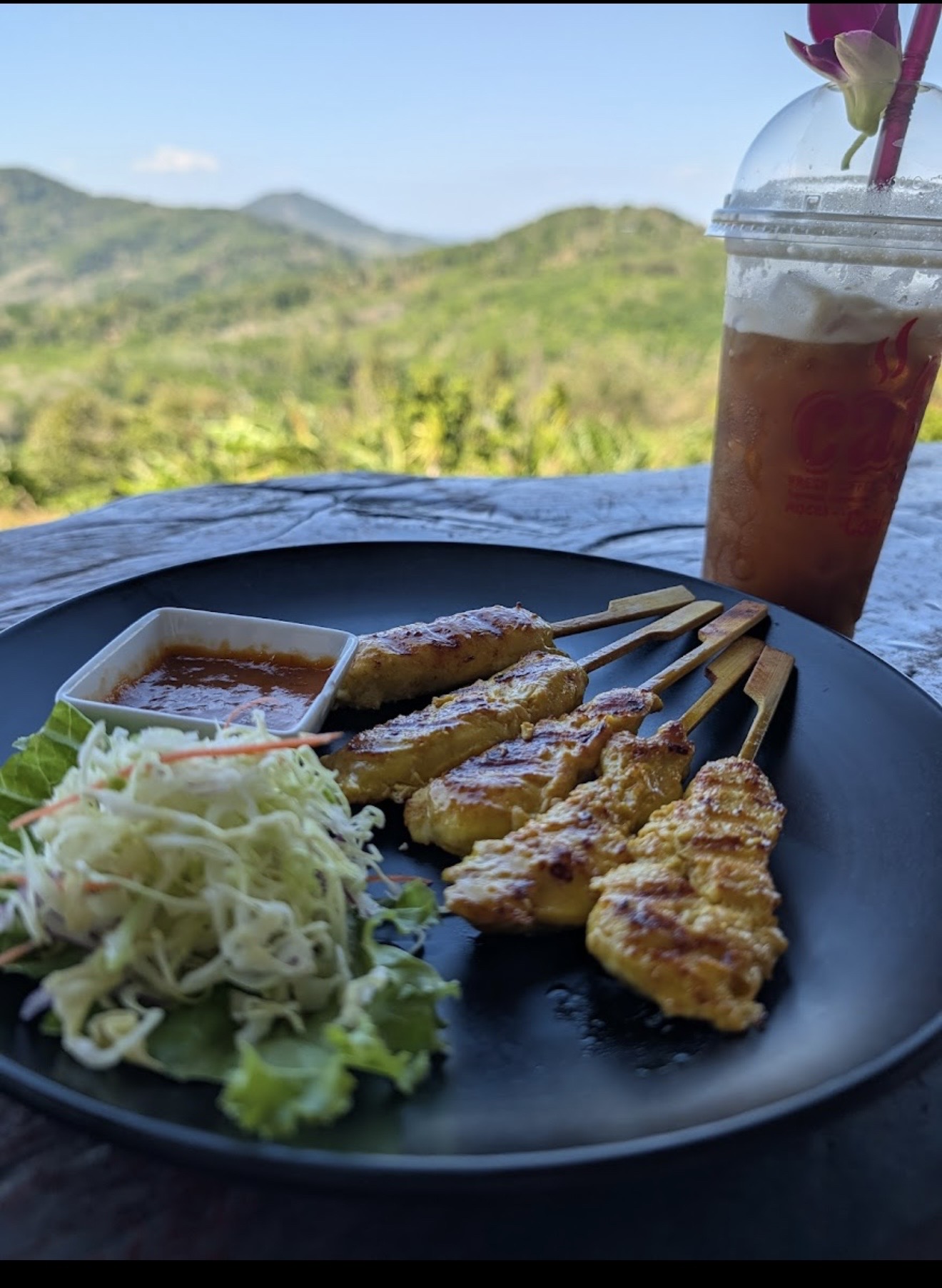 Chicken satay and iced tea with mountain view