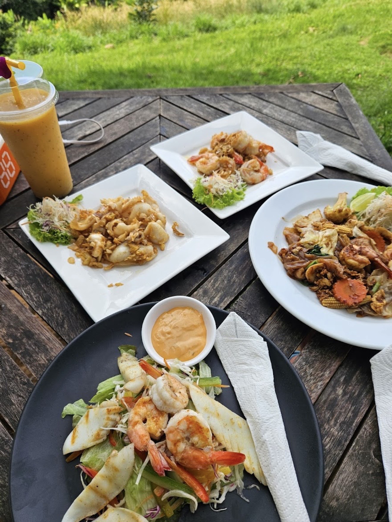 Seafood dishes and drink on outdoor table
